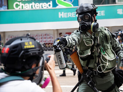 A riot police officer aims pepper spray at a journalist during a protest at Causeway Bay d