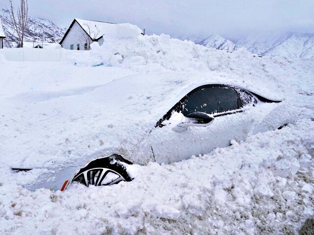 TOPSHOT - An abandoned electric car is buried in snow in Draper, Utah, on February 23, 2023. - Powerful winter storms lashed the United States on February 22, 2023, with heavy snow snarling travel across wide areas, even as unusual warmth was expected in others. Blizzards expected to dump up …