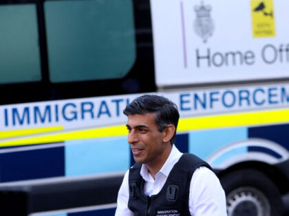 Britain's Prime Minister Rishi Sunak speaks to the press alongside an immigration van at W