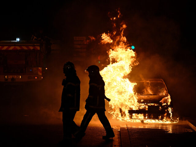 French firefighters walk past a burning car in Floirac on the outskirts of Bordeaux, south-western France on late June 29, 2023, during riots and incidents nationwide after the killing of a 17-year-old boy by a police officer's gunshot following a refusal to comply in a western suburb of Paris. (Photo …