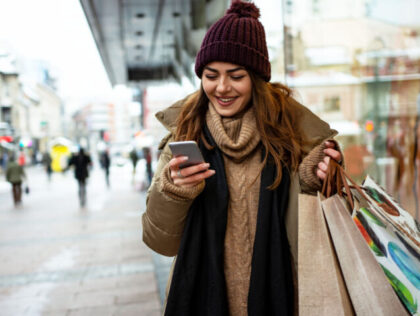 Beautiful woman using mobile phone during shopping in wintertime