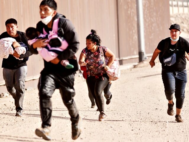 YUMA, ARIZONA- MAY 20: Immigrants, some carrying small children, run to cross through a ga