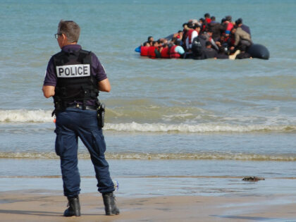 A French police officer stands on the beach as police work to prevent the departure of an