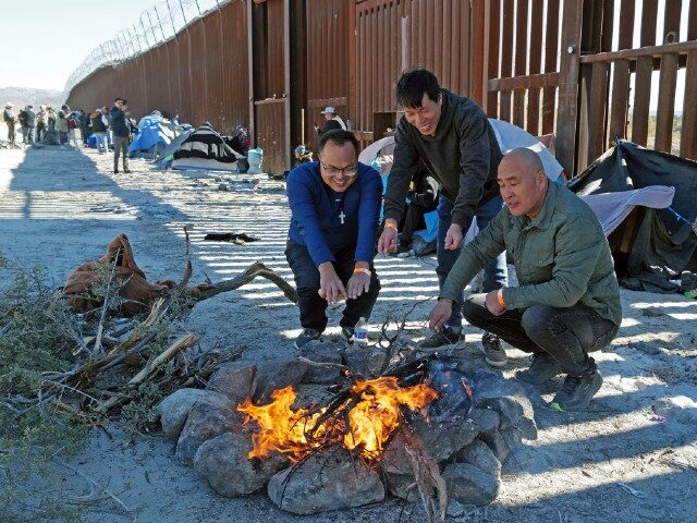 November 12: Chinese Migrants attempting to cross in to the U.S. from Mexico sit by a fire as they are detained by U.S. Customs and Border Protection at the border November 12, 2023 in Jacumba, California. (Photo by Nick Ut/Getty Images)