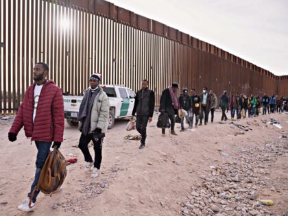 Migrants walk beside the US-Mexico border fence in Lukeville, Arizona, US, on Monday, Dec.