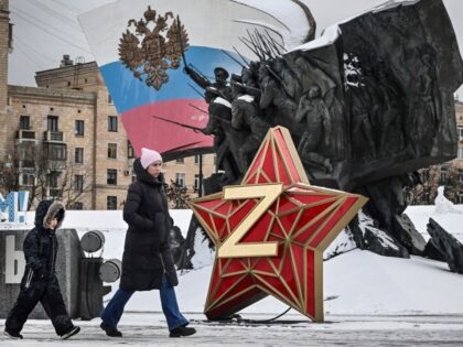 A woman and a child walk past a New Year decoration - Kremlin Star, bearing a Z letter, a