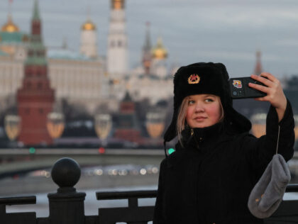 A woman takes a selfie picture with the Kremlin in distance on a frosty day in downtown Mo