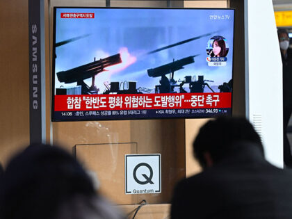 People watch a television screen showing a news broadcast with file footage of North Korea