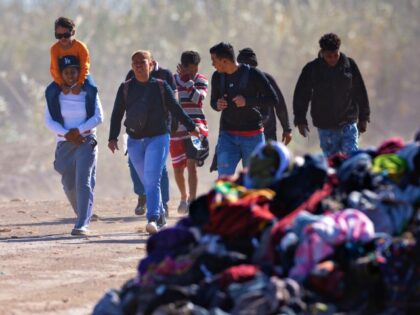EAGLE PASS, TEXAS - JANUARY 08: Immigrants from Venezuela walk past a pile of discarded m