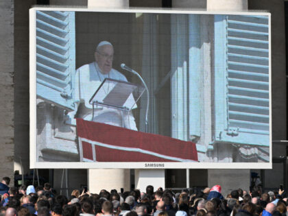 People look at a giant screen displaying Pope Francis' Angelus prayer, at St. Peter&#