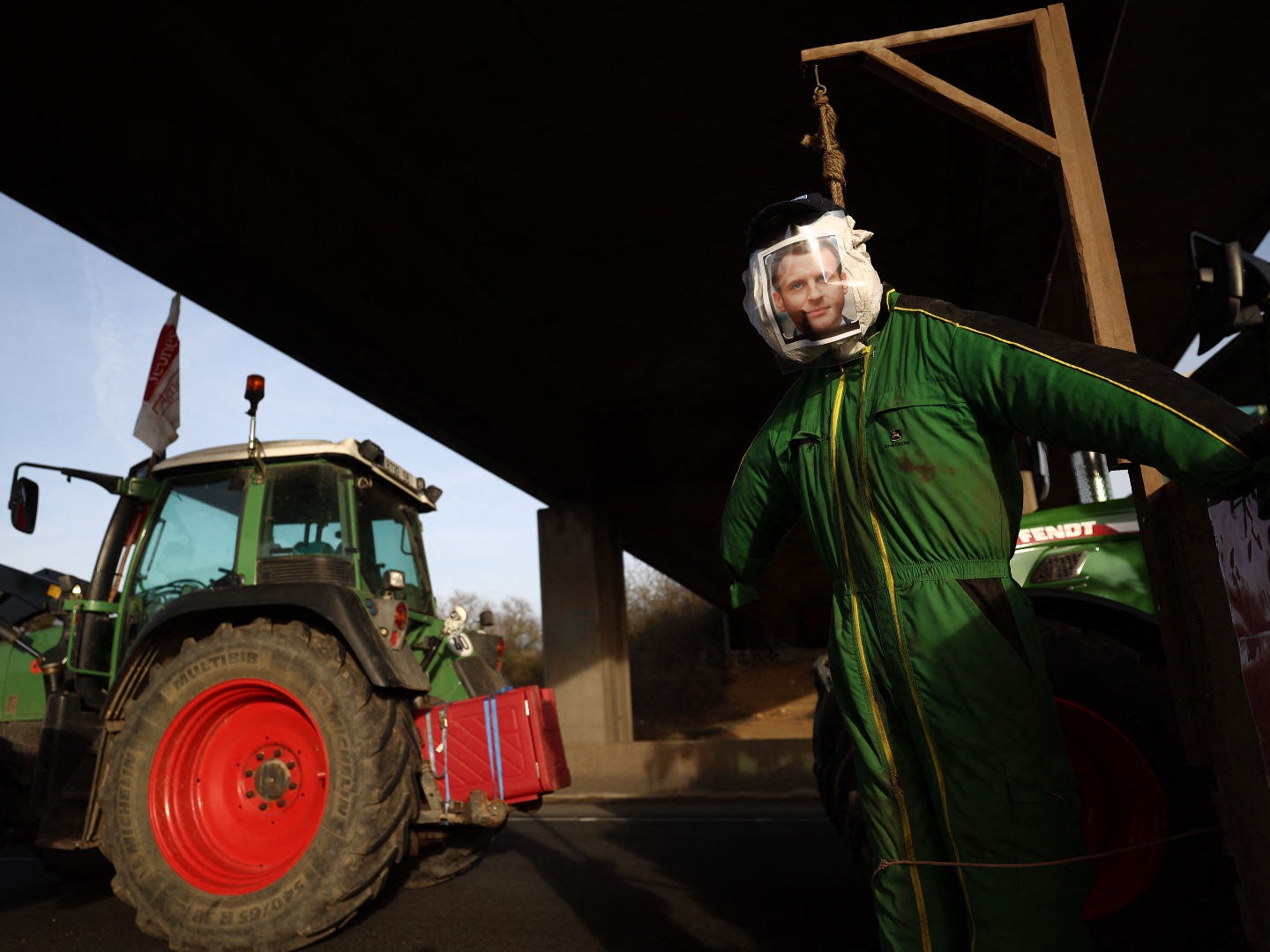 A mannequin in the effigy of French President Emmanuel Macron hangs next to tractors during a road blockage of the A6 highway near Villabe, south of Paris, on January 29, 2024, amid nationwide protests called by several farmers unions on pay, tax and regulations. Local branches of major farmer unions FNSEA and Jeunes Agriculteurs announced on January 27, 2024, a "siege of the capital for an indefinite period" starting at 2 p.m. on January 29, 2024, as some farmers deem the government's announcements in favor of the sector are insufficient. (Photo by Emmanuel Dunand / AFP) (Photo by EMMANUEL DUNAND/AFP via Getty Images)