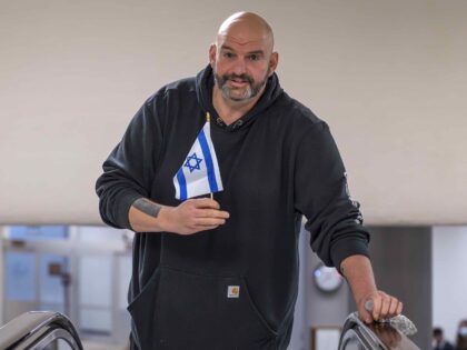 Sen. John Fetterman, D-Pa., holds a small Israel flag as he heads to the chamber for a vot