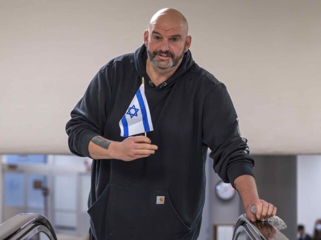 Sen. John Fetterman, D-Pa., holds a small Israel flag as he heads to the chamber for a vot