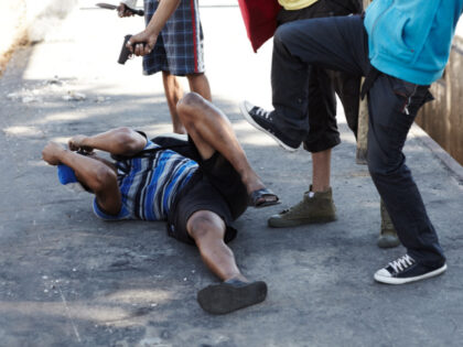 A man is on the ground while several men attack him (Stock photo via Getty).