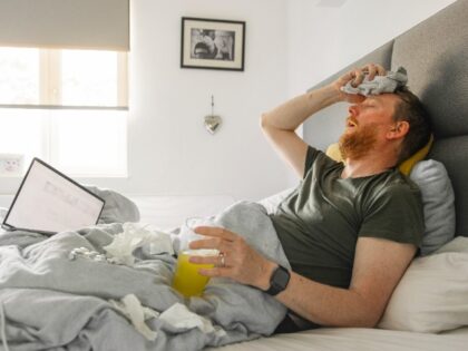A man lies in bed suffering from a flu-like respiratory illness (Stock photo via Getty).