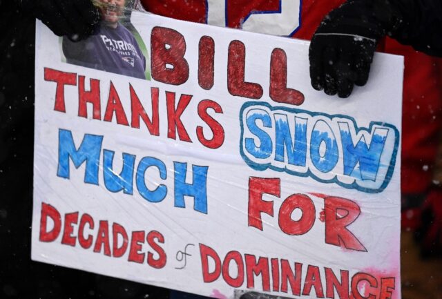 New England Patriots fans hold a sign "Bill, thanks snow much for decades of dominance" du