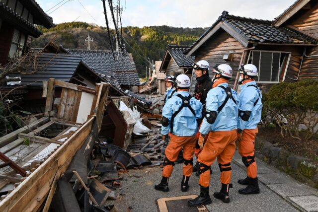 Firefighters inspect collapsed wooden houses in the city of Wajima on Japan's Noto Peninsu