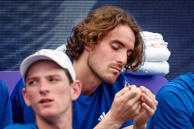 Greece's Stefanos Tsitsipas (R) sits on the team bench after pulling out of singles match