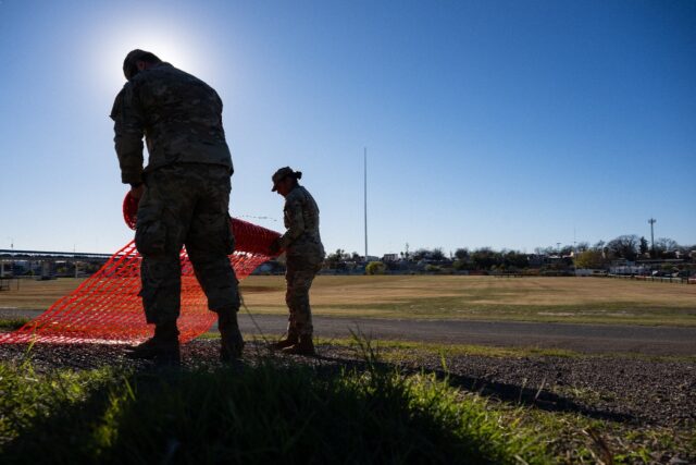 National Guard soldiers roll up fencing on the banks of the Rio Grande river at Shelby Par