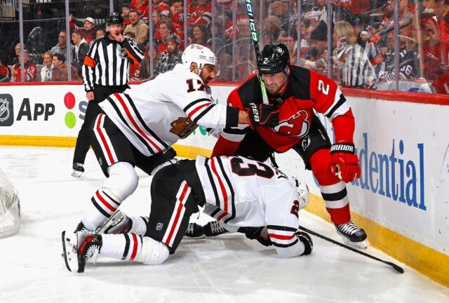 Nick Foligno and Philipp Kurashev of the NHL's Chicago Blackhawks go after Brendan Smith o