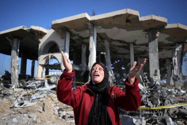 A Palestinian woman reacts in front of a destroyed building in the Al-Maghazi refugee camp