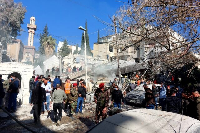 People and security forces gather in front of a building destroyed in a reported Israeli s