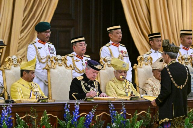Sultan Ibrahim Iskandar (C) signs documents during his oath-taking ceremony Wednesday at M