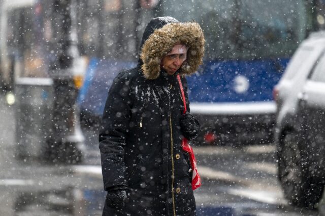 A woman walks as snow falls during a storm in New York City on January 19, 2024, but sever