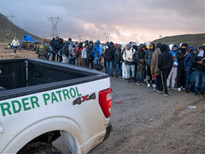 Asylum seekers wait in line to be processed by the Border Patrol at a makeshift camp near