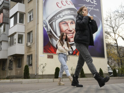 People walk past a billboard depicting the first cosmonaut Yuri Gagarin in Tiraspol, the c