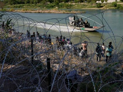 Migrants who crossed into the U.S. from Mexico are met with concertina wire along the Rio