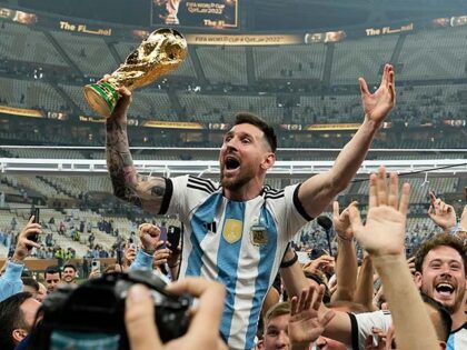 Argentina's Lionel Messi celebrates with the trophy in front of the fans after winnin