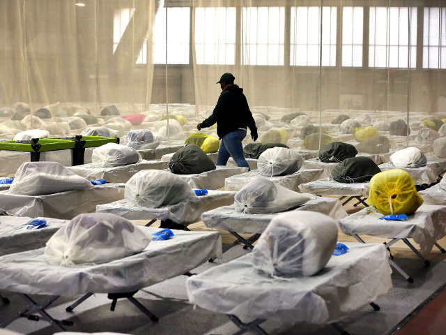Boston, MA - January 31: A worker walks through the over 300 Army cots on the gym floor as State and local officials toured the Melnea A. Cass Recreational Complex. The facility will be housing over 300 migrants. (Photo by John Tlumacki/The Boston Globe via Getty Images)