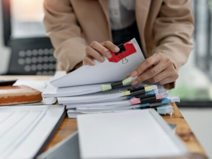 Bureaucrat, Businesswoman hands working on Stacks paper document files on her desk. Getty