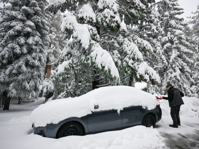 A man shovels snow off his car in the Cleveland National Forest, Wednesday, Feb. 7, 2024,