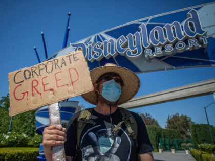 A man holds a sign in front of Disneyland Resort calling for higher safety standards befor