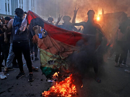 Supporters of Iraq's Sadrist movement burn a rainbow flag outside the Swedish embassy