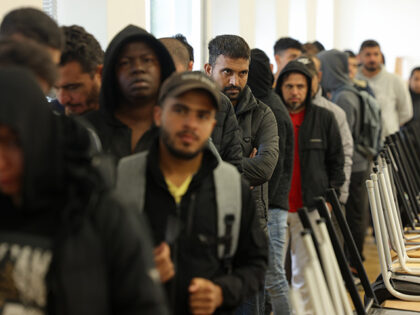 Men, many of them from Syria, queue for lunch at the initial reception facility for migran