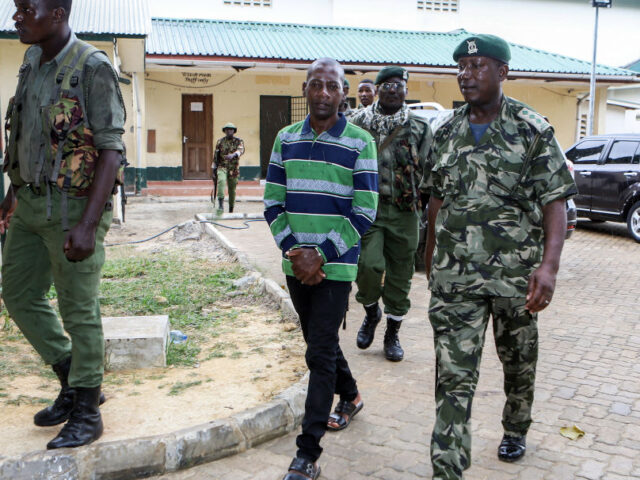 Self-proclaimed pastor Paul Nthenge Mackenzie (C) walks surrounded by Kenya Police Officer