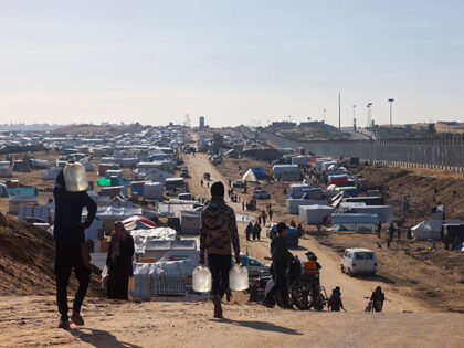 People ferry water at a makeshift tent camp for displaced Palestinians in Rafah near the b