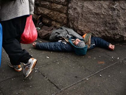 A person lays on the street in the Old Town Chinatown neighborhood in downtown Portland, O