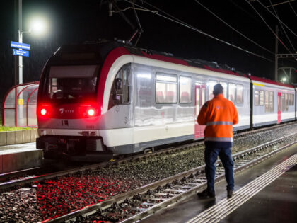 A railway technician stands next to a train, where passengers travelling from Yverdon to S