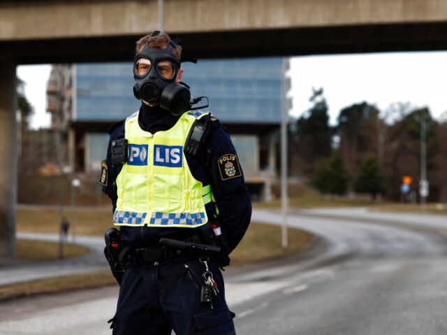 A Police officer wearing a gas mask stands guard at the scene after emergency services wer