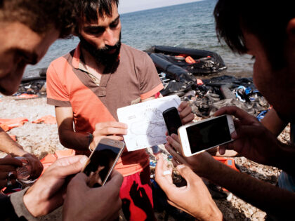 TOPSHOT - Refugees use mobile phones to take pictures of a map upon their arrival on Eftal