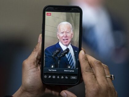 An attendee uses Facebook Live to record U.S. President Joe Biden speaking during an event