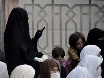 A Muslim pilgrim woman uses her phone, as she arrives for a prayer at Mecca's Grand Mosque