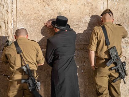 19 December 2022, Israel, Jerusalem: An ultra-Orthodox believer and two armed soldiers pra