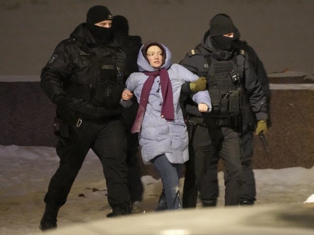 Police officers detain a woman who laid flowers for Alexei Navalny at the Memorial to Vict