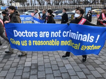 Doctors carry a banner reading "Doctors are not criminals!" as they march toward