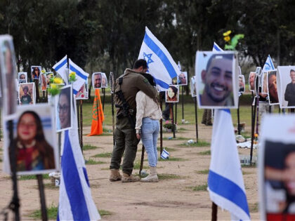 An Israeli soldier hugs a woman amid national flags and portraits of Israeli people taken